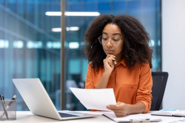 Ofis içinde evrak işleriyle uğraşan ciddi bir kadın finansör. Belgeleri ve evrakları elinde tutan odaklanmış bir muhasebeci. İş kadını verileri kontrol ediyor, ofis içinde çalışıyor..