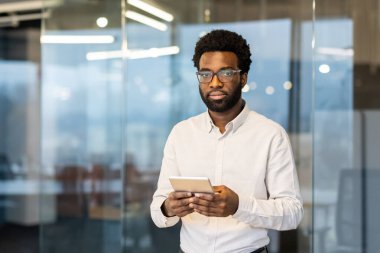Modern bir ofiste genç bir profesyonel, bir iş ortamında bağlantı ve teknoloji gösteren bir tablet tutuyor..
