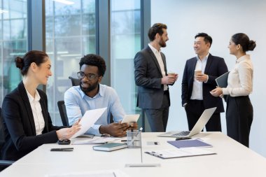 Bir grup profesyonel, modern ve parlak bir ofis ortamında iş birliği ve iletişim kuruyor..