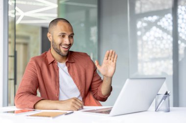 İş yerinde başarılı bir iş adamı video görüşmesi için laptop kullanıyor. İş yerindeki adam, iş arkadaşlarını ve ortaklarını uzaktan selamlıyor. İş toplantısı online konferans.