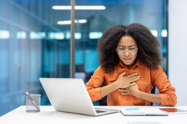 Ofisteki endişeli bir iş kadını göğüs ağrısı yaşar, muhtemelen stres ya da sağlıkla ilgilidir. Elleri göğsünde..