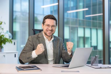 Başarılı bir işadamı ofisteki başarısını kutlar. Heyecanlı ve mutlu, yumrukları zafere sıkı sıkıya bağlı..