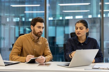 Ofis ortamında işbirliği yapan bir iş ekibi. Verileri ve stratejileri tartışan bir dizüstü bilgisayara odaklandılar..