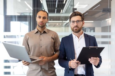 Modern ofis ortamında kendine güvenen iki farklı iş adamı iş için hazır bekliyor..