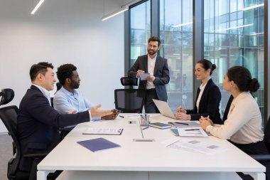 Modern ofis ortamında çeşitli iş adamları bir konferans masası etrafında ortak bir toplantı yapıyorlar..