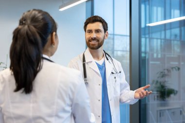 Beyaz önlüklü iki doktor konuşuyorlardı. Elleriyle el kol hareketi yapan adam..