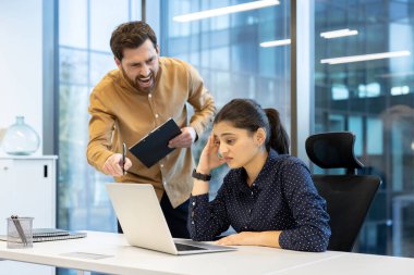 Öfkeli bir patron ofis ortamında çalışanını azarlıyor. İşçi de dizüstü bilgisayarına bakıyor..