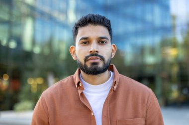 Modern bir binanın önünde sakallı genç bir adamın portresi, profesyonel bir estetik yaratıyor..