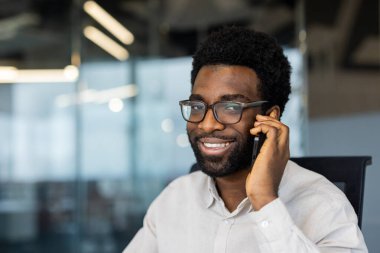 Çağdaş bir ofis ortamında oturan kendinden emin bir profesyonel telefon görüşmesi yapıyor..