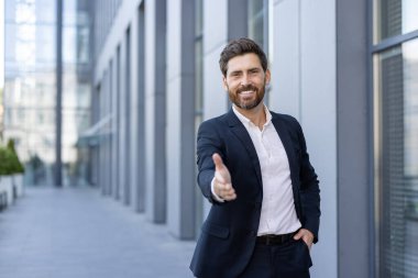 Kendine güvenen profesyonel bir erkek ofis ortamında el sıkışıyor, iş arkadaşlığı ve misafirperver bir tavır sergiliyor..