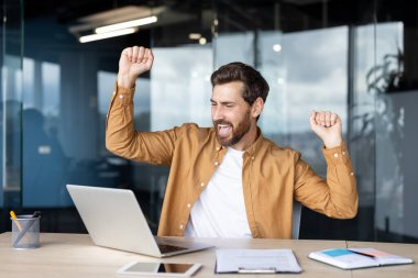 Masalarında oturmuş mutluluğu ve başarıyı ifade eden profesyonel bir kutlama. Neşeli jestleri coşku ve pozitiflik taşır, iş başarısı kavramlarını göstermek için mükemmeldir.