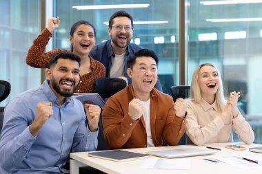 Çağdaş ofis ortamında sevinç ve başarı ifade eden, takım çalışması, işbirliği ve başarıyı yansıtan bir meslektaşlar takımı.