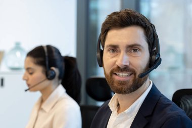 Müşteri hizmetleri temsilcileri, işbirliği ve profesyonelliği vurgulayarak, kulaklıklarla modern bir ofis ortamında gayretle çalışıyorlar. Müşteri desteği için ideal resim