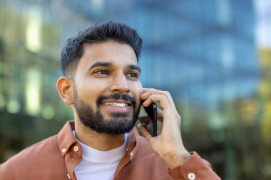 Kentli bir ortamda cep telefonuyla konuşan kendinden emin bir birey pozitifliği ve profesyonelliği aktarıyor. Arkaplanda modern, dinamik ve iş ortamı vurgulanıyor