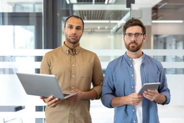Modern bir ofiste, takım çalışması ve teknoloji kullanımını iş ortamında sergileyen iki profesyonelin dinamik işbirliği.