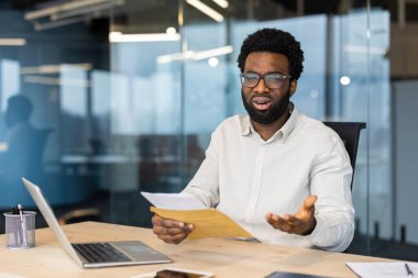 Masada oturan bir işadamı bir mektup okurken şaşırmış ya da hayal kırıklığına uğramış görünüyor. Kapalı ofis ortamında karmaşa gibi duygular vurgulanıyor