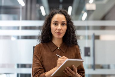 Modern ofis ortamında odaklanmış profesyonel bir iş adamı not defterine notlar yazıyor. Profesyonelliği, detaylara dikkati ve kurumsal iş kültürünü temsil eder..