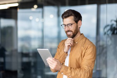 İş profesyoneli, çalışma analizi için bir tablet kullanmakla meşgul, odak ve verimliliği yansıtıyor.