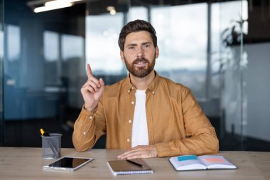 Modern ofiste oturan kendine güveni tam bir adam, yukarıyı işaret ederek tartışmalara giriyor.