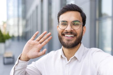 Gözlük takan ve sakal sallayan neşeli bir insan şehir ortamında gülümserken, mutluluğu ve arkadaşlığı iletirken..