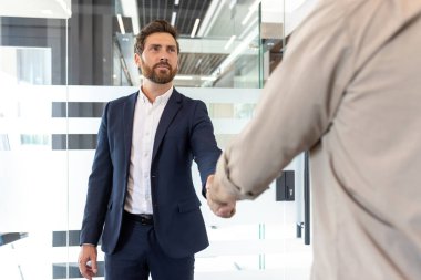 Çağdaş ofis ortamındaki iki kişi arasındaki profesyonel hoş geldin jesti, anlaşmayı veya işbirliğini simgeliyor.