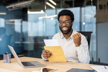 İş ortamında iyi haberler alırken heyecan gösteren kendine güvenen bir profesyonel. Ayar pozitifliği, modern işyeri atmosferini, başarıyı ve kariyer başarısını taşır.