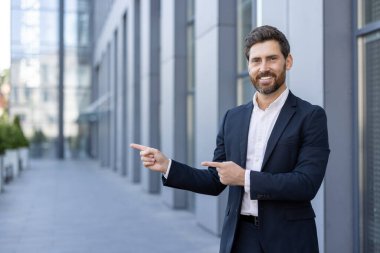 Takım elbiseli bir iş adamı, çağdaş bir binanın dış cephesinde güvenli bir şekilde dışarı çıkar. Olumlu davranış, bir işletme veya şirket ortamında güven, profesyonellik ve başarı taşır