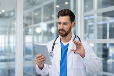 Doctor in white coat and stethoscope holding digital tablet and medicine bottle, providing a telemedicine consultation or online prescription assistance to a patient