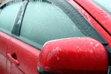 Kırmızı araba buzla kaplı. Arabanın buzlu yüzeyi..