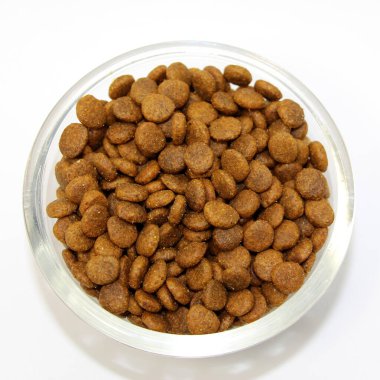 Beyaz bir arka planda cam bir kasede kediler ve köpekler için kuru, dengeli yiyecekler. Üst görünüm