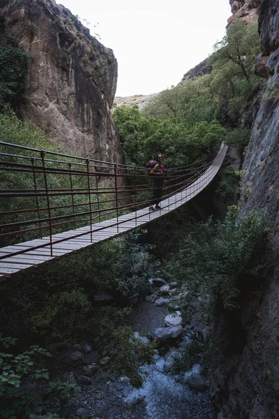 Woman crossing a bridge in the mountains