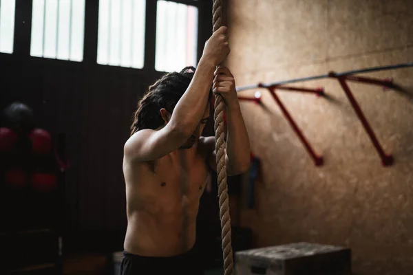 Spor salonundaki adam ipe tırmanıyor.