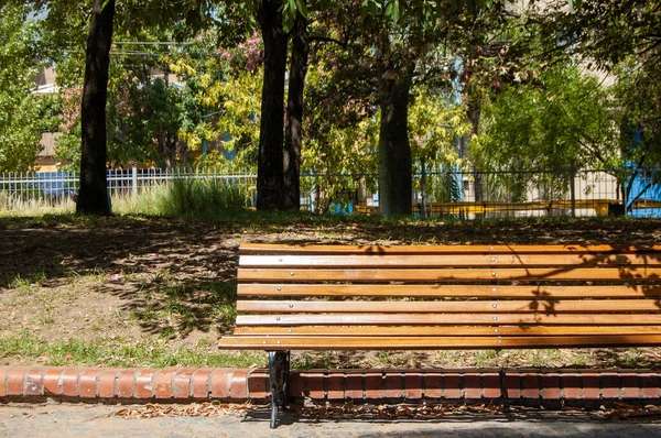 banco de plaza de madera rodeado de arboles