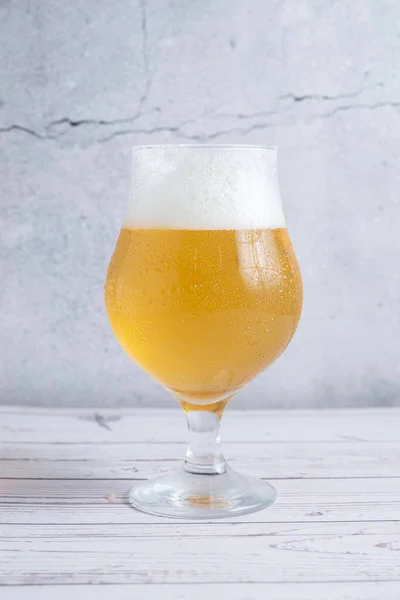 copa con cerveza rubia con espumaa