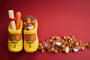 Saint Nicholas - Sinterklaas day with shoe, carrot and traditional sweets on red background. clipart