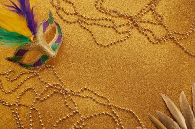 Mardi gras or carnival mask with beads on gold glowing background. Venetian mask. High quality photo