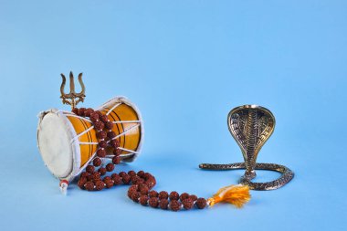 Shivaratri background with Shivas trident, Pellet Drum Damroo musical instrument ans snake . Hindu festival Maha Shivratri.