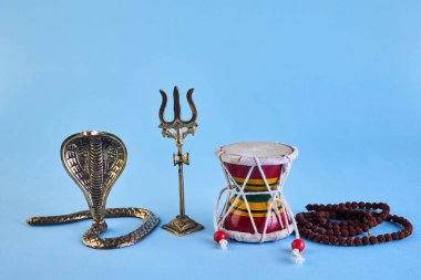 Shivaratri background with Shivas trident, Pellet Drum Damroo musical instrument ans snake . Hindu festival Maha Shivratri.