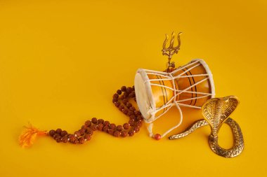 Shivaratri background with Shivas trident, Pellet Drum Damroo musical instrument ans snake . Hindu festival Maha Shivratri.