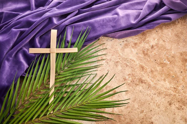 Lent season, Holy week and Good friday concept. Palm leave and cross on stone background.