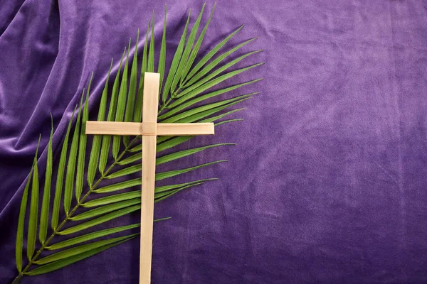 Lent season, Holy week and Good friday concept. Palm leave and cross on purple background.