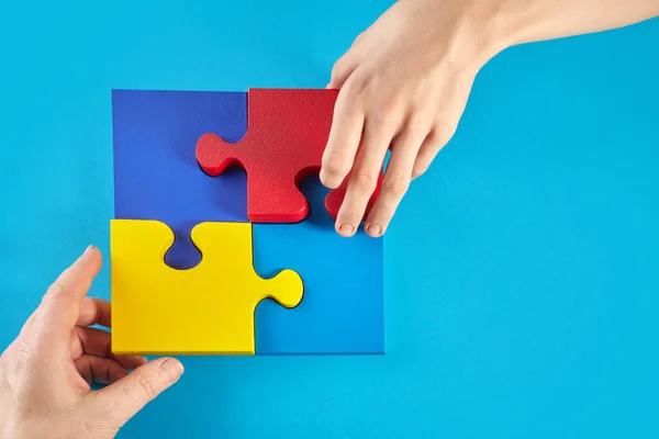 Father and autistic son hands holding jigsaw puzzle shape. Autism spectrum disorder family support concept. World Autism Awareness Day.