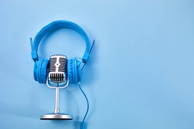 Dünya müzik günü konsepti. Müzik kulaklığı ve mavi arka planda bir mikrofon..