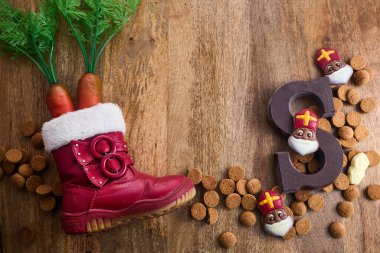 Dutch holiday Sinterklaas background. Children shoe with carrots for Nicholas horse, traditional sweets pepernoten and chocolate letter. clipart