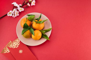 Çin Yeni Yılı. Kırmızı zarf, çiçekler, mandalina, kırmızı arka planda festival süslemeleri. Düz yatış, üst görünüm.