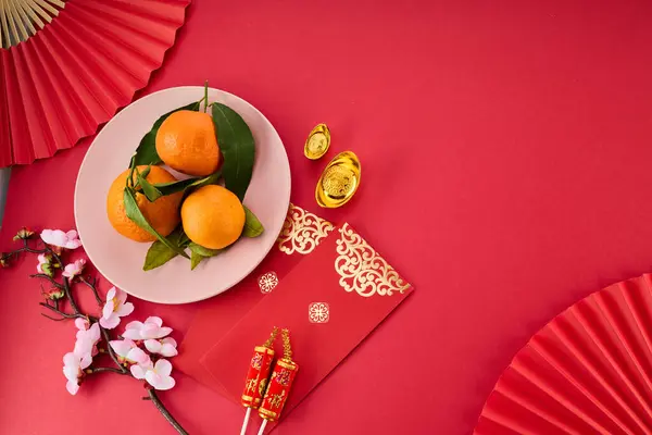 Chinese New Year. Red packet envelope, flowers, mandarins, festival decorations on red background. Flat lay, top view.