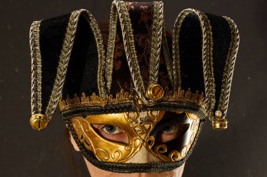 Karanlık arka plan duvarında karnaval maskesi takan bir kadının yakın plan portresi..