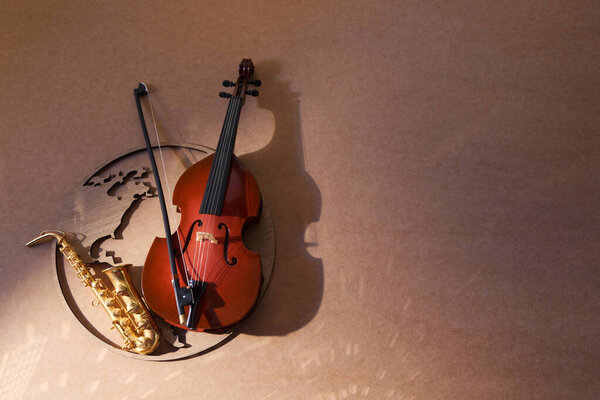 An artistic composition of a violin and saxophone bathed in warm light with shadows.