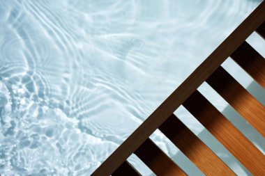 Açık mavi havuz suyu ahşap bir güvertenin altında dalgalanır..