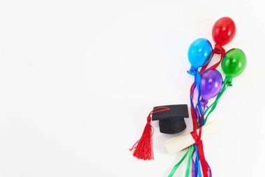Mezuniyet şapkaları, diplomalar ve beyaz üzerine renkli balonlar..